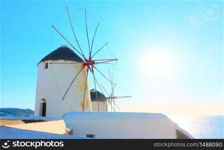 Old white windmillls in Mykonos island against the cloudless light blue sky with shining sun, Greece. Greek landscape with space for your own text