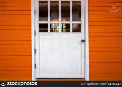 Old white wooden door in an orange wooden wall, house, empty interior, texture, square background