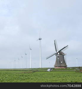 old windmill goliath at roodeschool in the dutch province of groningen between row of modern wind turbines