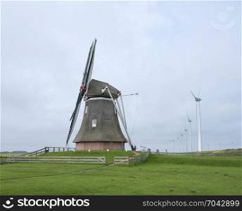 old windmill goliath at roodeschool in the dutch province of groningen between row of modern wind turbines
