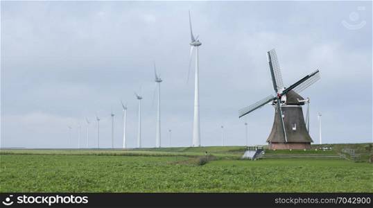 old windmill goliath at roodeschool in the dutch province of groningen between row of modern wind turbines