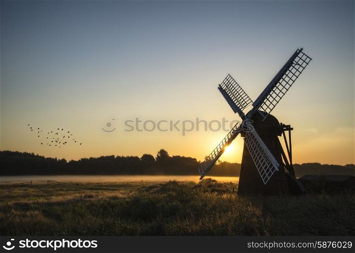 Old windmill in foggy English countryside landscape