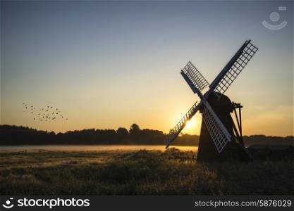 Old windmill in foggy English countryside landscape