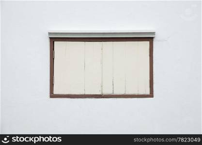 Old window on a white wall. Old white wall with a small window of the house.