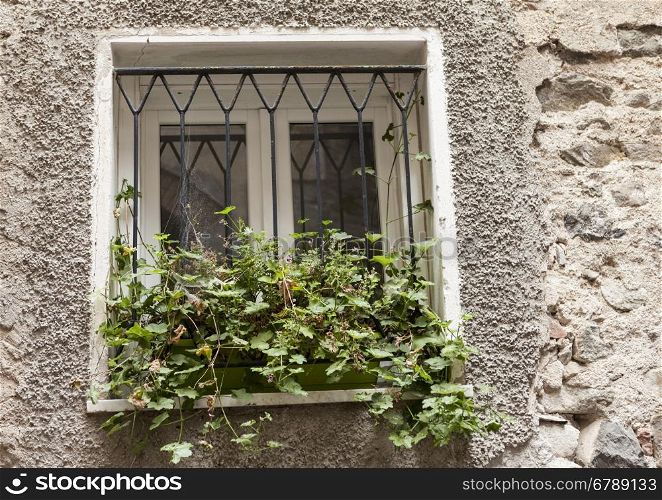 Old window with closed shutters with flowers on the window sill on the stone wall. Italian Village. Old window with closed shutters with flowers on the window sill on the stone wall. Italian Village.