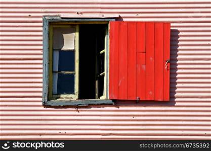 Old window with coloful red shutter in La Boca, Buenos Aires, Argentina