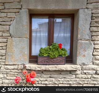 old window with flowers on a stone wall