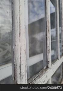 Old window with peeling white paint on the frame focus on foreground window perspective