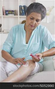 Old woman applying ointment on leg