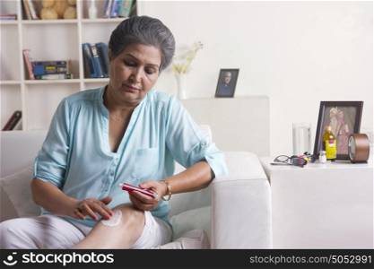 Old woman applying ointment on leg