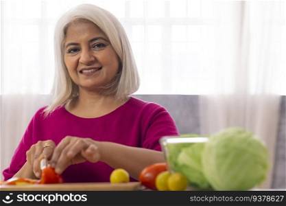 Old woman chopping vegetables in the kitchen
