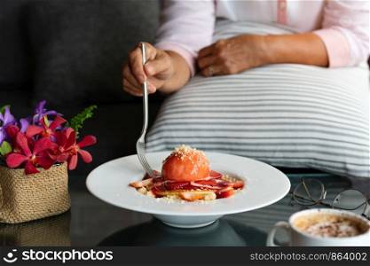 old woman hold folk with freshly homemade Pancakes Strawberry Crumble on white dessert plate
