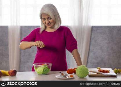Old woman making vegetable salad in the kitchen