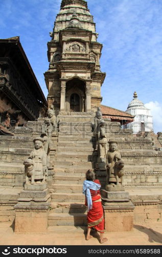 Old woman near steps on temple on the durbar in Bhaktapur, Nepal