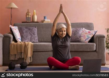 Old woman practising yoga with online class