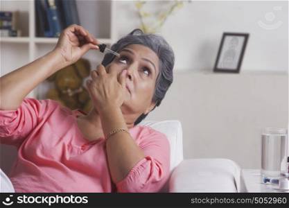 Old woman putting eye drops
