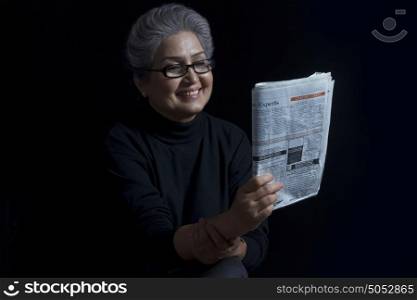 Old woman reading newspaper smiling