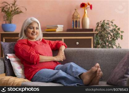 Old woman relaxing on sofa in living room