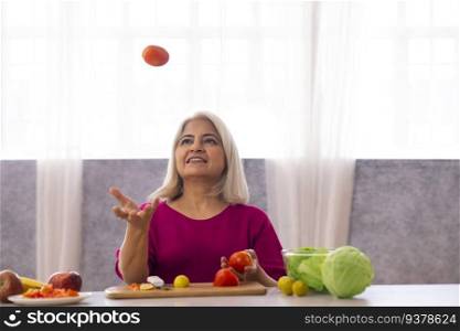 Old woman throwing tomato in the kitchen