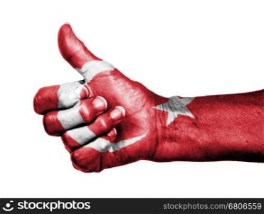 Old woman with arthritis giving the thumbs up sign, wrapped in flag pattern, Turkey