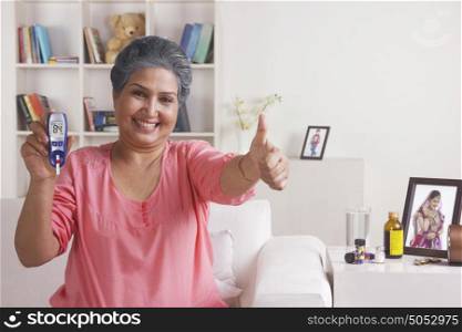 Old woman with glucose meter giving thumbs up