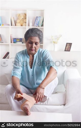 Old woman wrapping bandage on foot