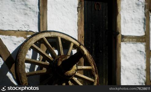 old wood wheel and black door at white house