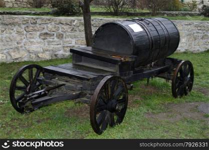 Old wooden barrel on cart. Vintage black barrel wagon transports water.. Vintage black barrel wagon transports water