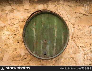 Old wooden barrel on stone farmhouse wall. Wooden barrel hanging on old rustic stone wall of farmhouse