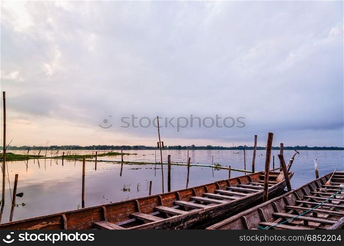 Old wooden boat floating on the water amidst the natural landscape of the morning at Kwan Phayao Lake in Phayao Province, Thailand