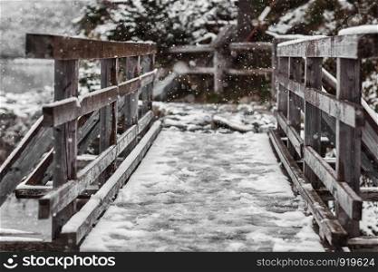 Old wooden bridge in winter in the mountains.. Old wooden bridge in winter in the mountains. Snow-covered bridge over the mountain river