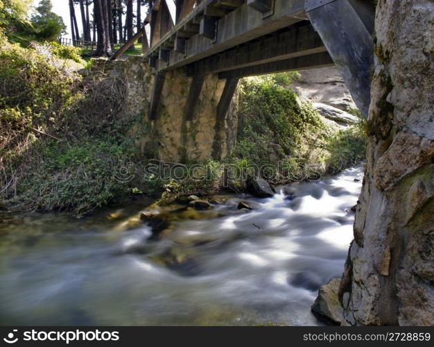 old wooden bridge over a river of silky waters