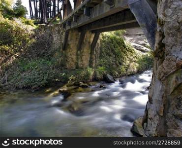 old wooden bridge over a river of silky waters