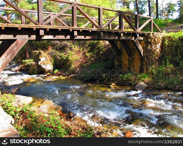 old wooden bridge over a stream in a forest