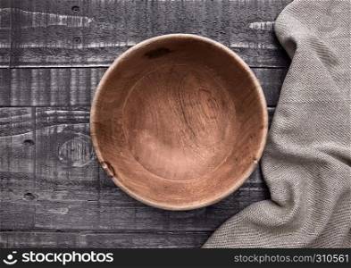 Old wooden brown bowl with kitchen cloth on wooden background