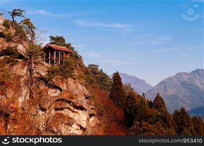 Old wooden buildings on rock cliff in evening at Yamadera Risshaku ji temple complex under blue sky in autumn. Yamagata - Japan