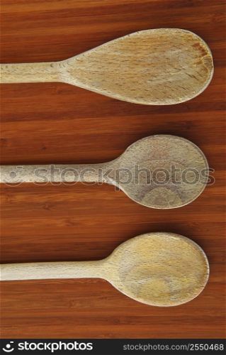 Old wooden cooking spoons on a cutting board in a kitchen