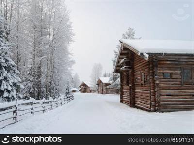 Old wooden country houses, covered with snow in northern open air museum Malye Korely near Arkhanglesk, Russia. Frosty winter day.