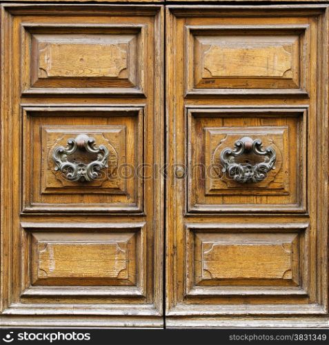 Old wooden door with metal door knockers in Lucca, Tuscany, Italy