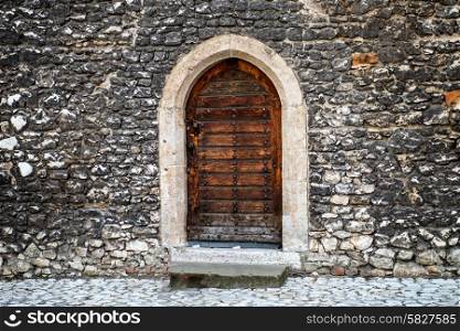 Old wooden door with stone wall on the ancient street