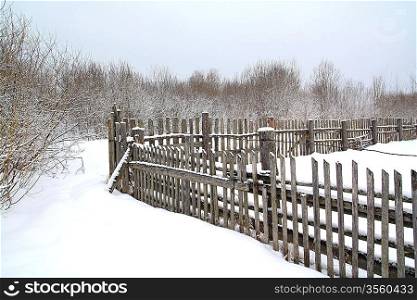 old wooden fence on winter snow
