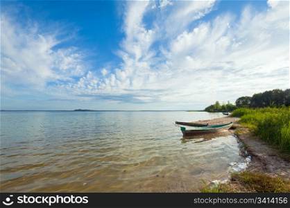Old wooden fishing boat near the lake shore and summer sky behind (Svityaz, Ukraine)