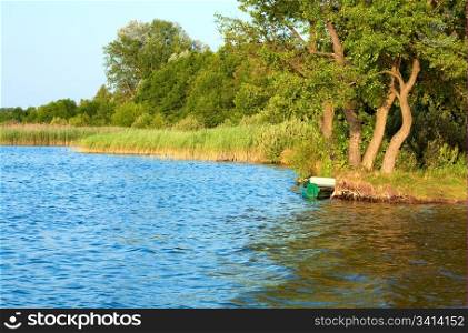 Old wooden fishing boat near the summer lake shore (Svityaz, Ukraine)