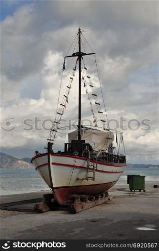 Old wooden fishing boat on shore for repair.
