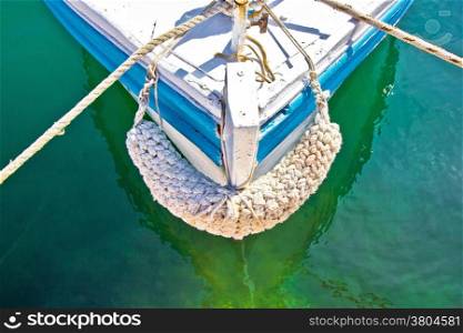 Old wooden fishing boat prow in green sea water
