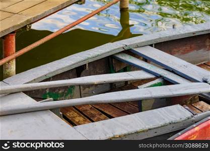 Old wooden fishing boat with paddles on lake shore. Summer activity.. Boat on lake shore
