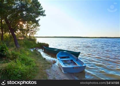 Old wooden fishing boats near the summer lake shore (Svityaz, Ukraine)