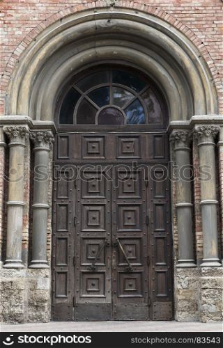 old wooden front door to a historic building of red bricks