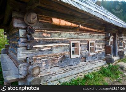 Old wooden house in Autumn mountain village (Carpathian , Ukraine) and trembita (Guzul music pipe) on wall
