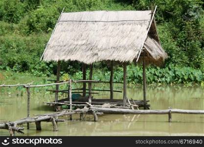 Old wooden hut on the pond in laos